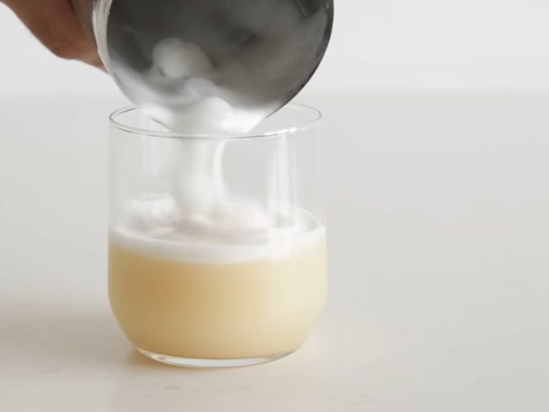 Osoba dodaje penu u Whiskey Sour