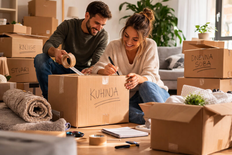 Par organizuje selidbu i označava kutije sa stvarima u dnevnoj sobi novog doma