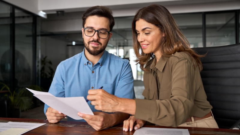 Knjigovođa objašnjava preduzetniku dokument dok zajedno pregledaju papire u kancelariji