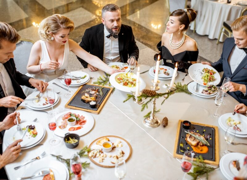 prikaz grupe ljudi elegantno obulčenih koji sede u restoranu