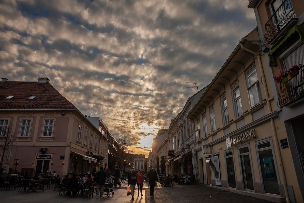 Ulica u centru Zemuna sa pešacima, kafićima i starom arhitekturom u večernjim satima.