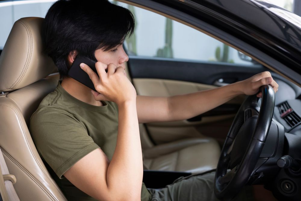 Vozač iz zaustavljenog automobila telefonom poziva pomoć na putu.